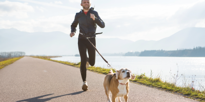 Muž a pes běží canicross podél řeky