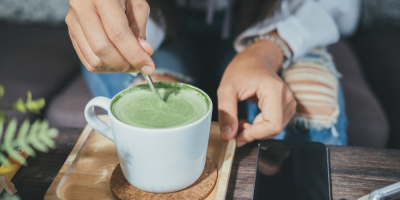 Člověk míchá lžičkou matcha tea v hrnku