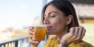 Žena v letních šatech pije čaj kombucha