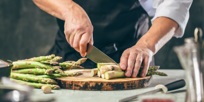 Kuchař krájí chřest na prkénku