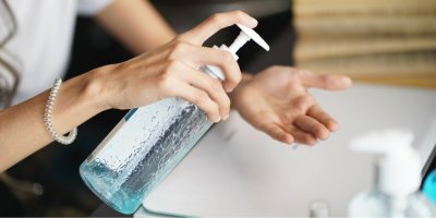 Žena dávkuje antibakteriální gel z velké nádoby do dlaně