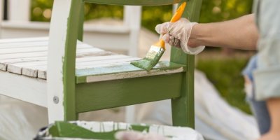 Žena natírá dřevěnou zahradní židli