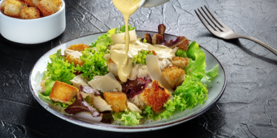 Záběr na zálivku, která teče na kuřecí Caesar salát