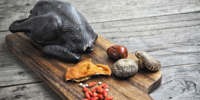 Černá slepice na prkénku s houbami