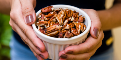 Žena drží mističku s pekanovými ořechy