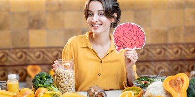 Žena drží obrázek mozku a před sebou má zdravé jídlo