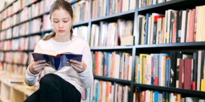 Dívka si v knihkupectví čte knihu