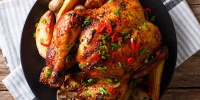 Pečené celé kuře s houbami a bramborami na talíři na stole