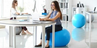 Žena pracuje na počítači a sedí na gymnastickém míči