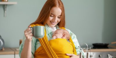 Maminka s miminem v šátku drží hrneček