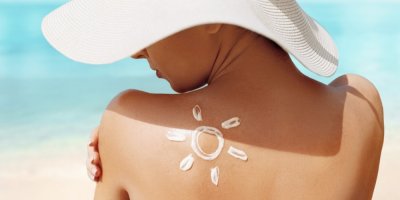 Žena v klobouku a opalovacím krémem na zádech