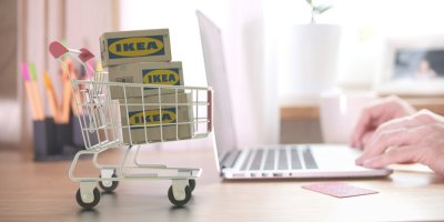 Košík s krabicemi IKEA a člověk používající notebook