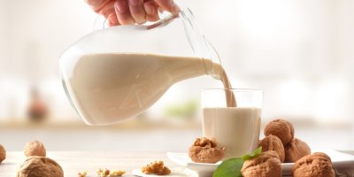 Muž plní sklenici s ořechovým nápojem ze džbánu