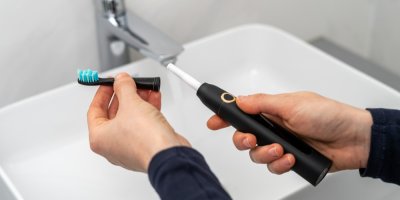 Člověk nasazuje hlavici na tělo elektrického kartáčku