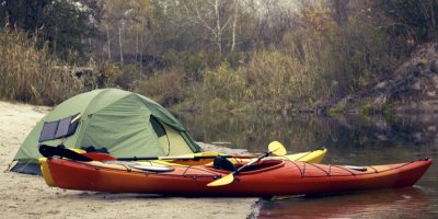 Kajak na říční pláži u postaveného stanu