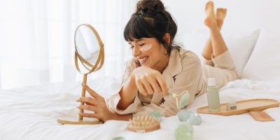 Žena leží na posteli a má na obličeji masku