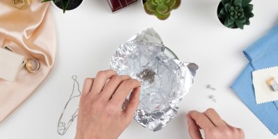 Člověk čistí šperky v misce pomocí alobalu