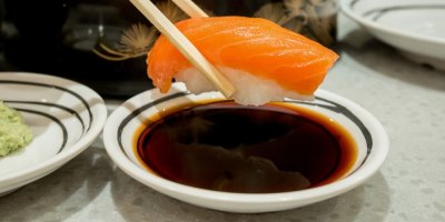 Záběr na namáčení kousku sushi do sójové omáčky