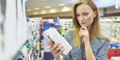 Žena si v obchodě prohlíží informace na krabici mléka