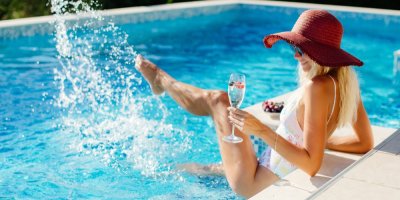 Žena si dává sklenici šampaňského u bazénu