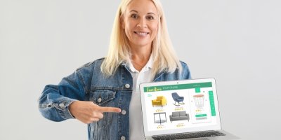 Žena ukazuje prstem na notebook, na kterém je stránka s bazarem nábytku