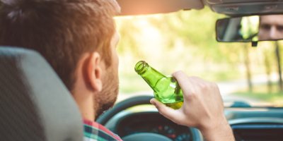 Muž pije pivo za volantem