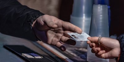 Ruka podávající občanku ke kontrole při nákupu alkoholu