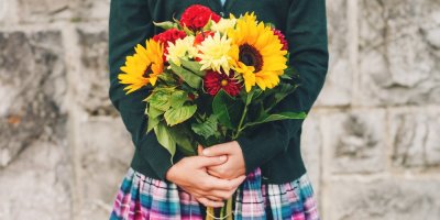 Dívka ve školní uniformě drží květinu