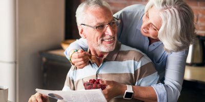 Šťastní prarodiče si povídají a smějí se při jídle v kuchyni