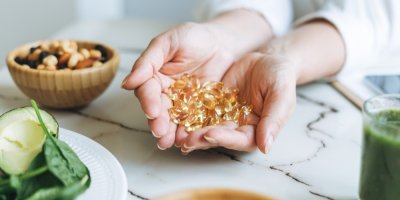 Žena drží kapsle s rybím tukem v dlaních