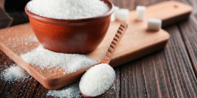 Cukr krystal na dřevěné lžíci a v misce