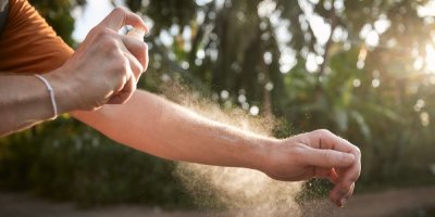 Záběr na muže, který se stříká repelentem