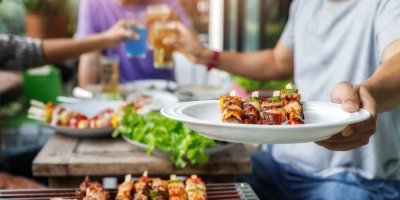 Muž podává talíř s grilovanými pokrmy