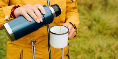 Člověk nalévá nápoj z termosky do hrnku