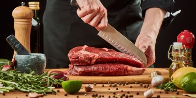 Muž krájí syrové maso nožem