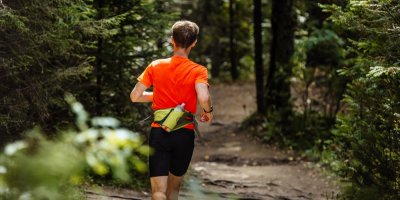 Muž běhá v lese, kolem pasu má ledvinku s lahví na vodu