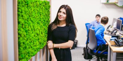 Žena stojí u stěny s mechem