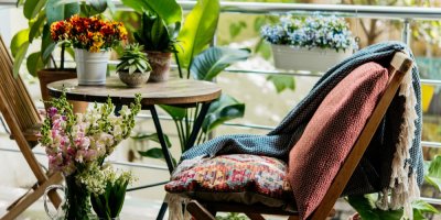 Útulný balkon s dekami, polštáři a květinami