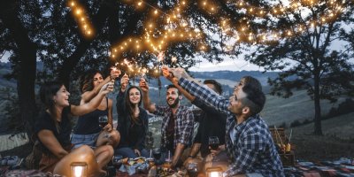 Skupina lidí si užívá piknikový večer se svíčkami a světýlky