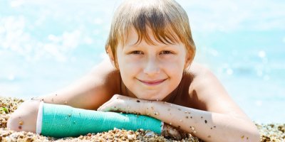 Kluk se sádrou na pláži u moře