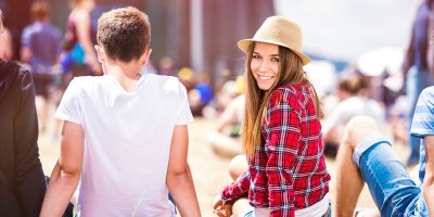 Muž a žena sedí na zemi na festivalu, žena má na hlavě klobouk