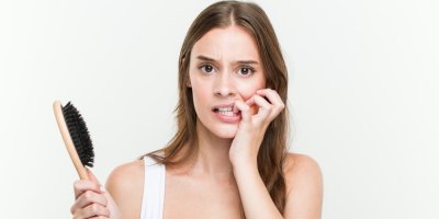 Žena s kartáček v ruce si kouše nehty