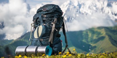 Turistický batoh s karimatkou sedící naproti vysoké hoře