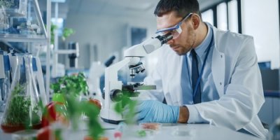 Muž kouká do mikroskopu