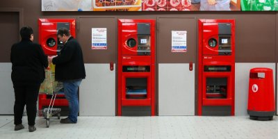 Dva lidé v obchodě u přístroje na vratné lahve