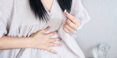 Žena si dává prášek na bolest břicha