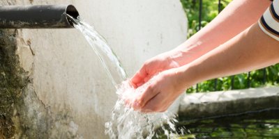 Žena si myje ruce pod tekoucí vodou ze zdi