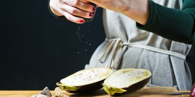 Žena solí rozkrojený lilek