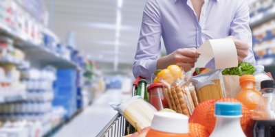 Žena si čte účtenku nad nákupním vozíkem