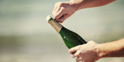 Muž otevírá láhev šampaňského